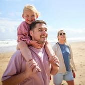 Couple walking on a beach with a toddler on shoulders