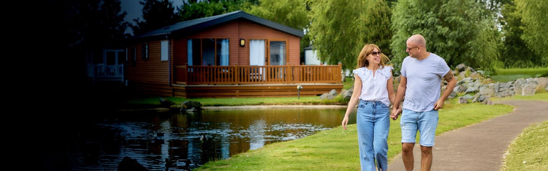 Couple walking alongside lake with lodge in background