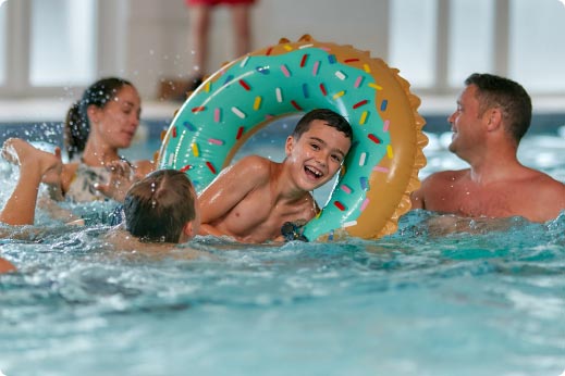 Family playing in the indoor swimming pool with an inflatable donut