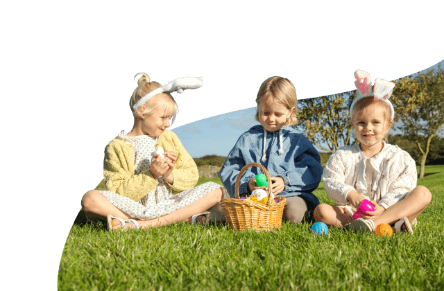 Little girls wearing bunny ears collecting Easter eggs