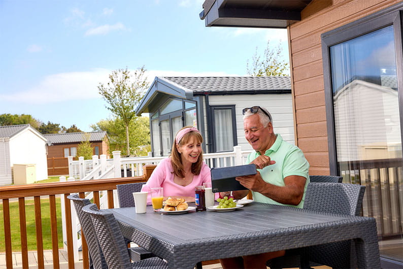 A couple enjoying a meal on the veranda of their caravan