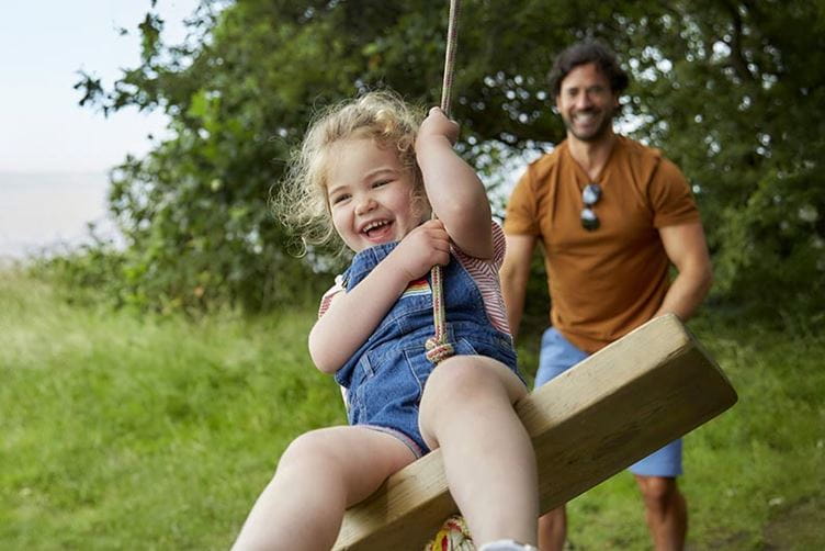 Parent pushing child on swing