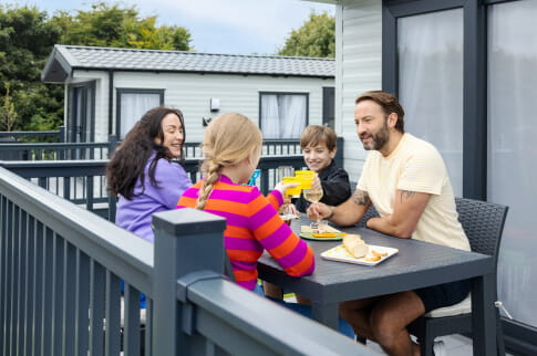 A family sat around a table on a caravan veranda