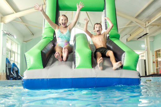 two children going down an inflatable slide in a swimming pool