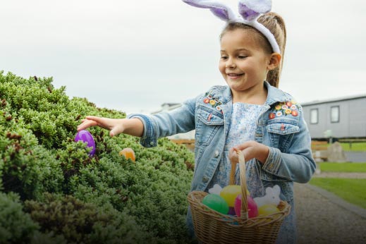 Little girl wearing bunny ears collecting easter eggs
