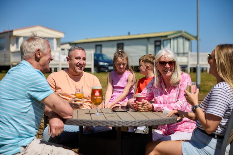 Group of people sitting in the sunshine smiling and drinking