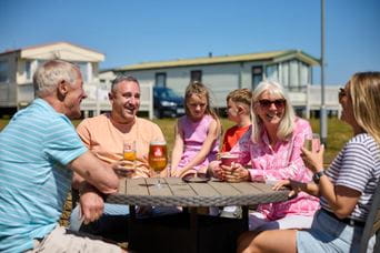 Group of people sitting in the sunshine smiling and drinking