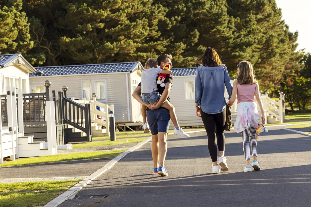 Family walking into the distance hand in hand through the sunny caravan park