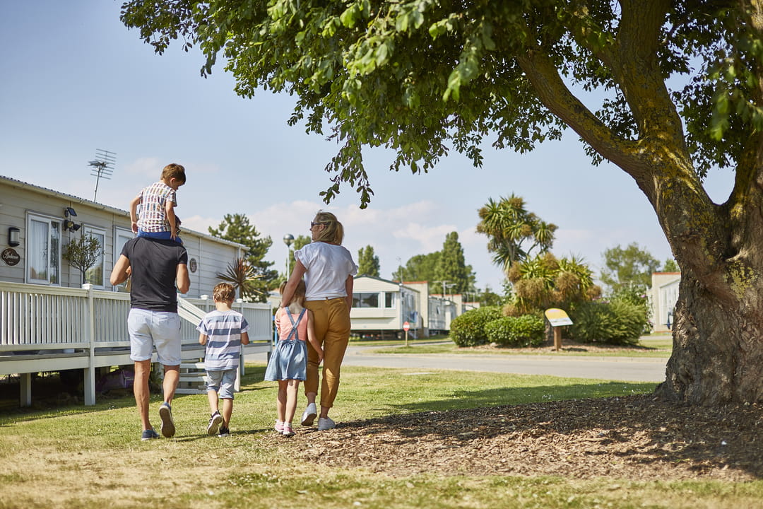 Family of four walking in the sunshine into the distance of Parkdean Resorts