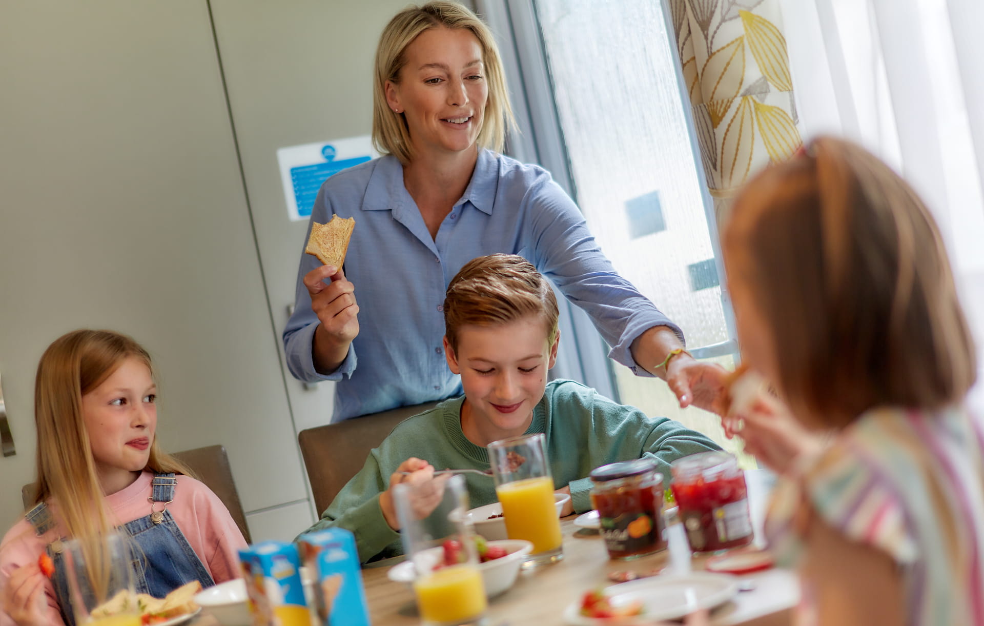 Family sat around a caravan table eating and drinking fresh orange juice