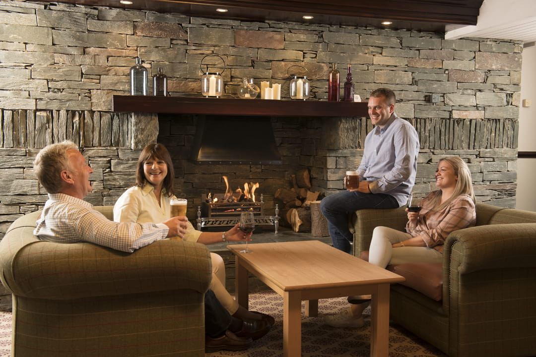 Two couples sat on comfy sofas laughing and enjoying drinks 
