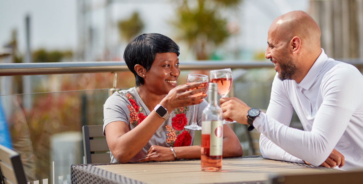 Couple on veranda clinking wine glasses