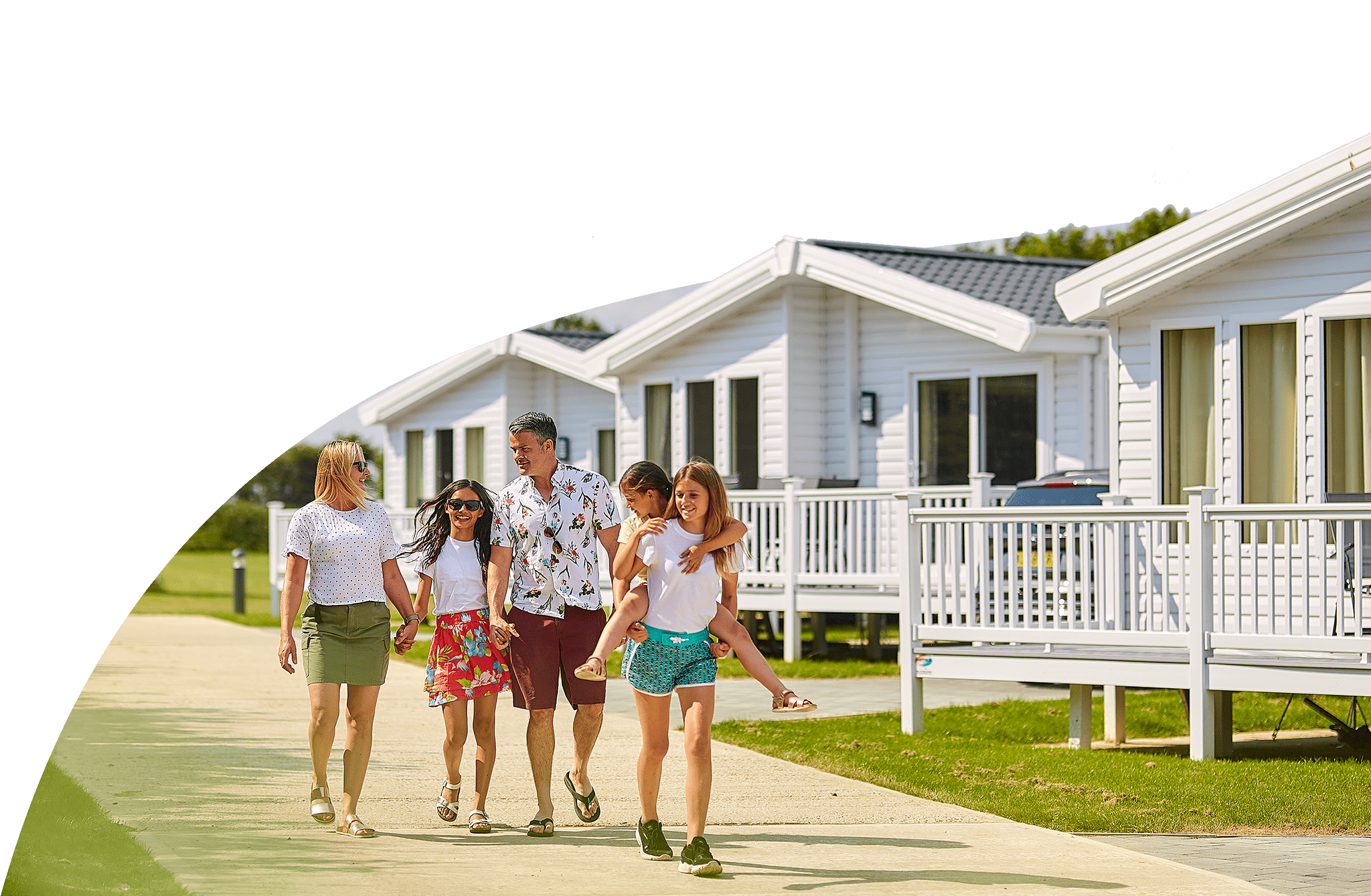 Family walking in the sunshine through a Parkdean Resorts caravan park