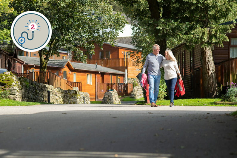 A couple walking through a holiday park with lodges in the background