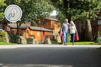 A couple walking through a holiday park with lodges in the background