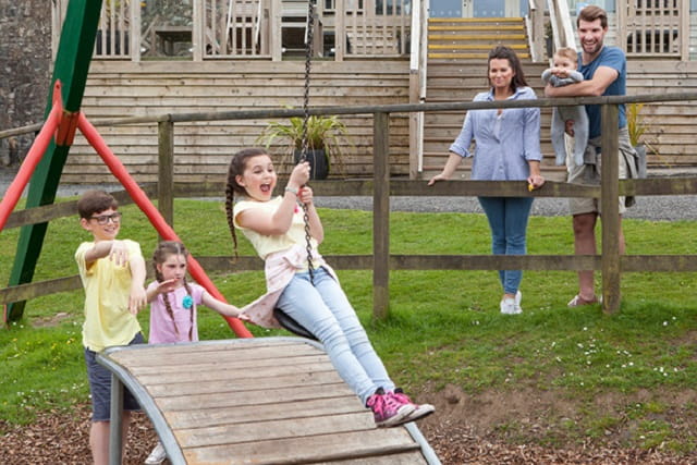 parents watching children on a swing