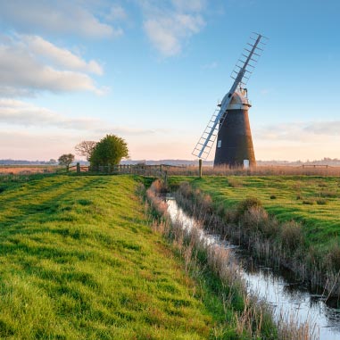 a windmill in a field with a river passing by it