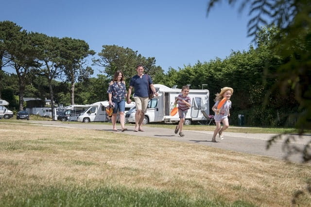 A family walking past touring caravans at Breydon Water Holiday Park