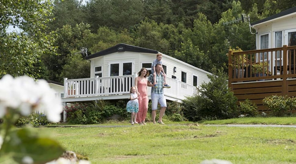 A family walking through the lodges and caravans at Brynowen Holiday Park