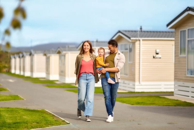 A couple walking and smiling with a young girl on the man's hip