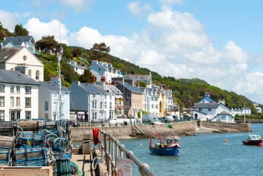 White houses on the seafront with small boats sailing out