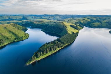 Picturesque green hills rising above a blue sea on a cloudy day