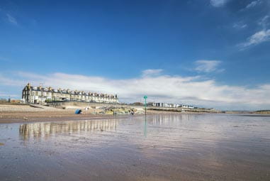 Row of white houses on a beach reflecting in the sea