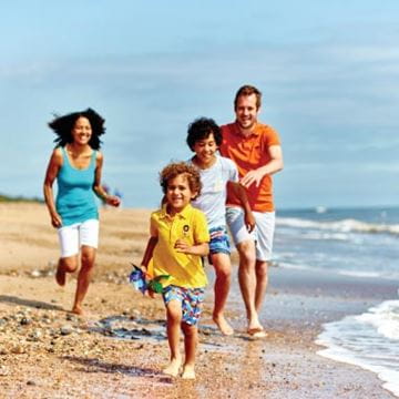 Family walking on a beach by the sea line