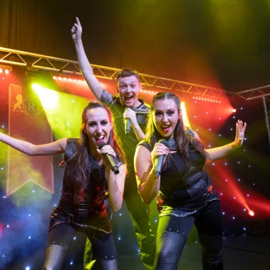 Entertainers with microphones performing on stage with coloured lights