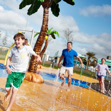 Family running through sprinklers
