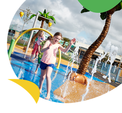 A girl running through the wet outdoor play area at Camber Sands Holiday Park