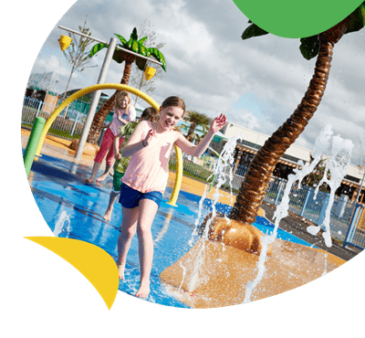 A girl running through the wet outdoor play area at Camber Sands Holiday Park