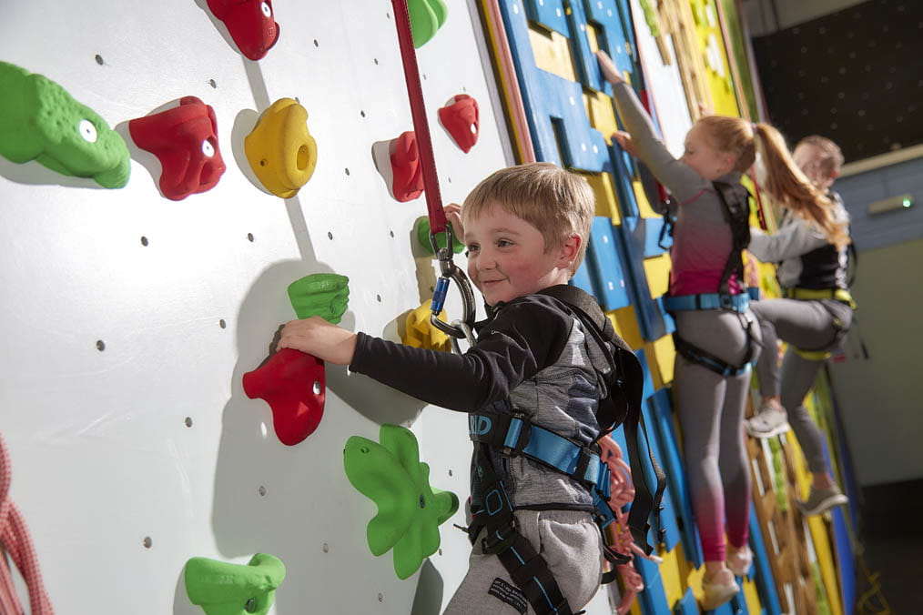 Three children climbing the climbing wall