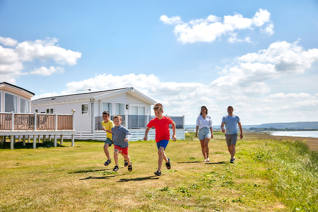 A family walking past holiday lodges on the coast at Carmarthen Bay Holiday Park