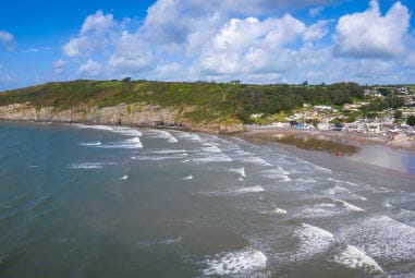 gentle waves rolling towards green cliffs
