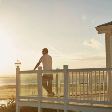 A man looking out at the sea from his lodge