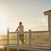 A man looking out at the sea from his lodge
