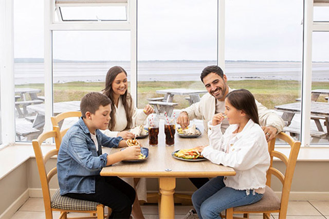 A family tucking into a meal in the restaurant with a sea view