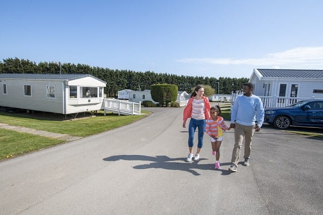 A family walking past holiday accommodation at Cayton Bay Holiday Park
