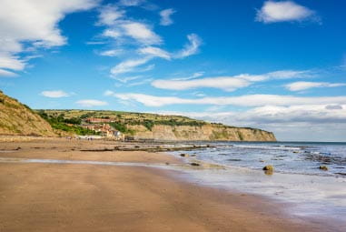 a sandy beach surrounded by cliffs and the sea