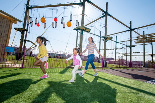 2 kids and mum running by the high ropes course 