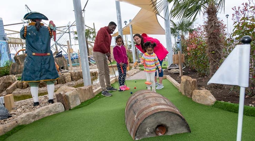 A family playing crazy golf at Cayton Bay