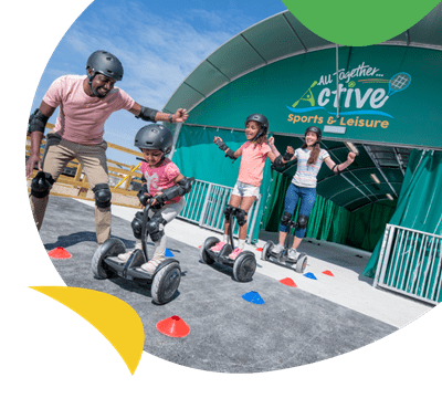 A family on hoverboards outside the activities hub at Cayton Bay Holiday Park