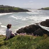 a woman relaxing on a hill by the coast