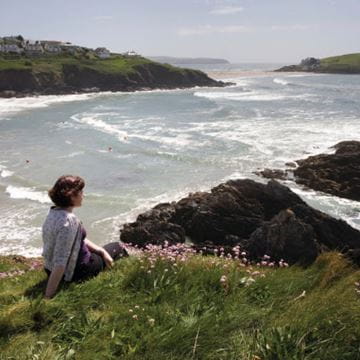 a woman relaxing on a hill by the coast
