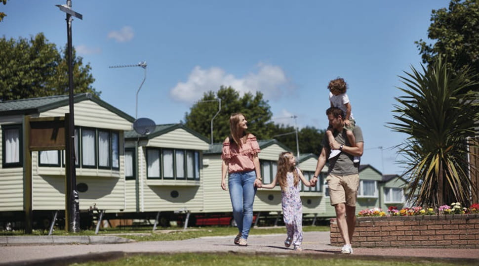 family walking past caravans on a sunny day
