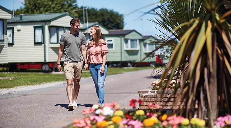 couple walking past caravans