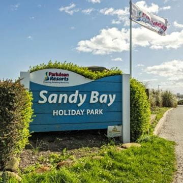 "Sandy Bay Holiday Park" sign with flag