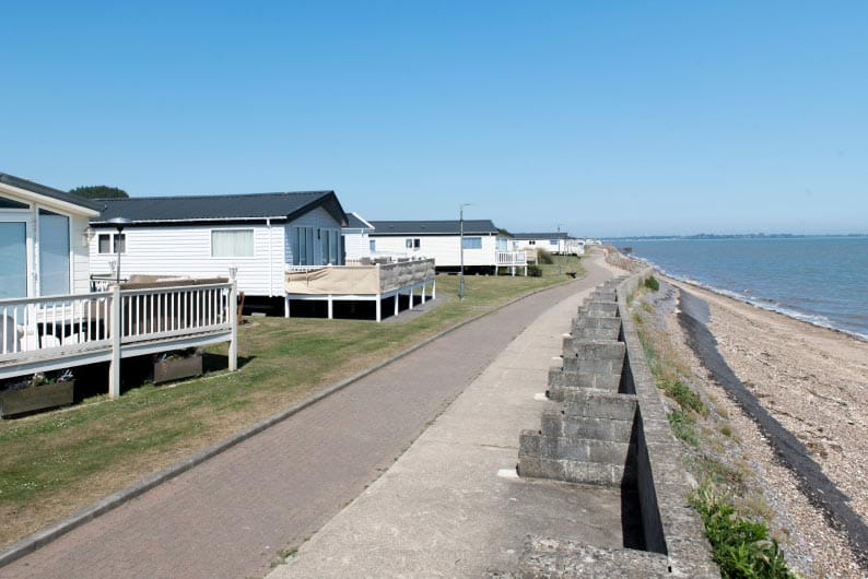 Holiday park homes with fenced patios next to the beach