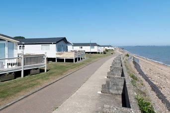 Holiday park homes with fenced patios next to the beach